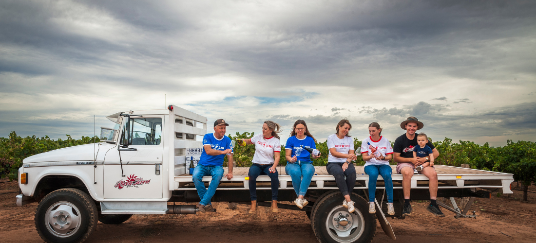 Family holding wine sitting on the back of a truck